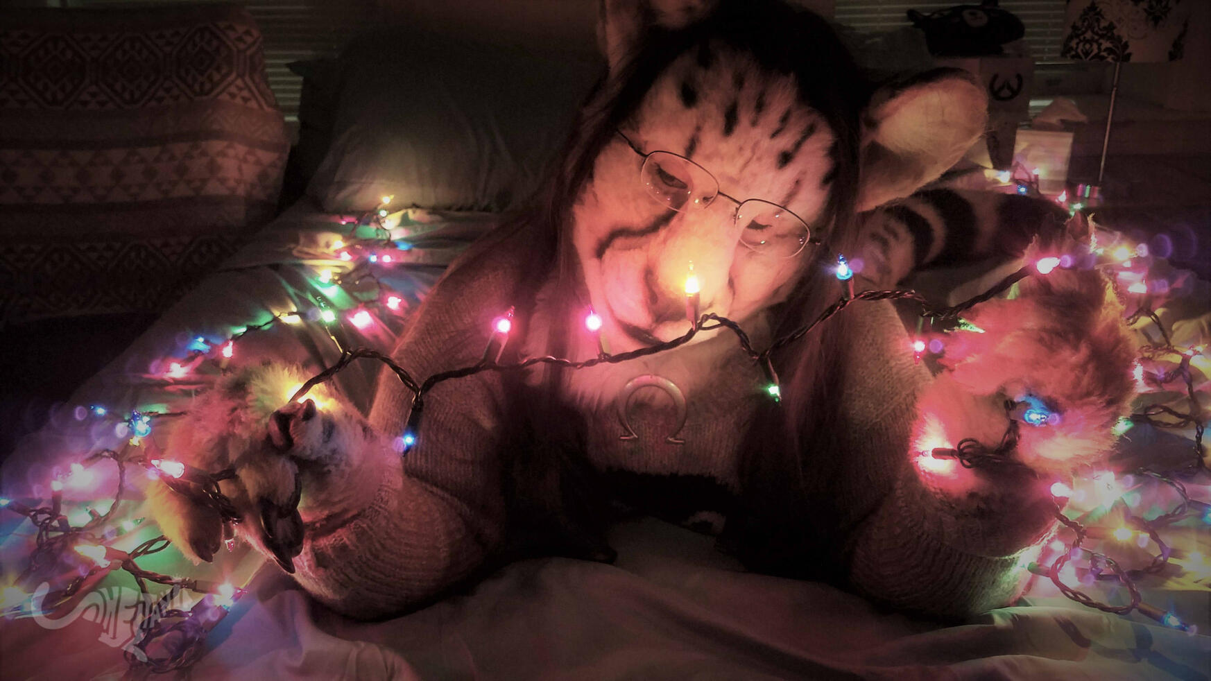 Shetani on a bed in the dark, holding and looking fondly at a string of illuminated fairy lights. Soft and muted colors