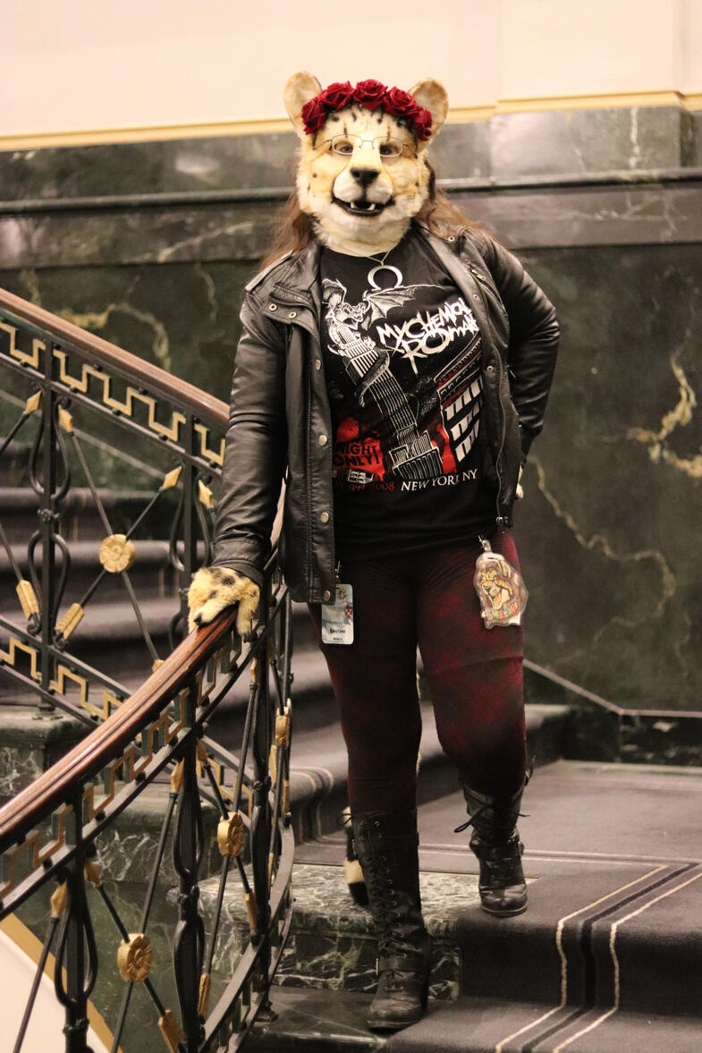 Shetani posing on an ornate staircase, also wearing a black leather jacket, boots, MCR shirt, and matching leggings
