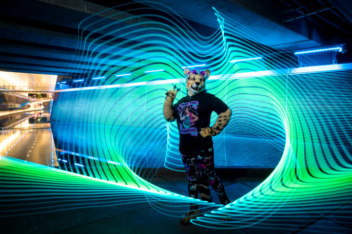 Shetani holding up the peace sign with very cool blue and green light painting around/behind her