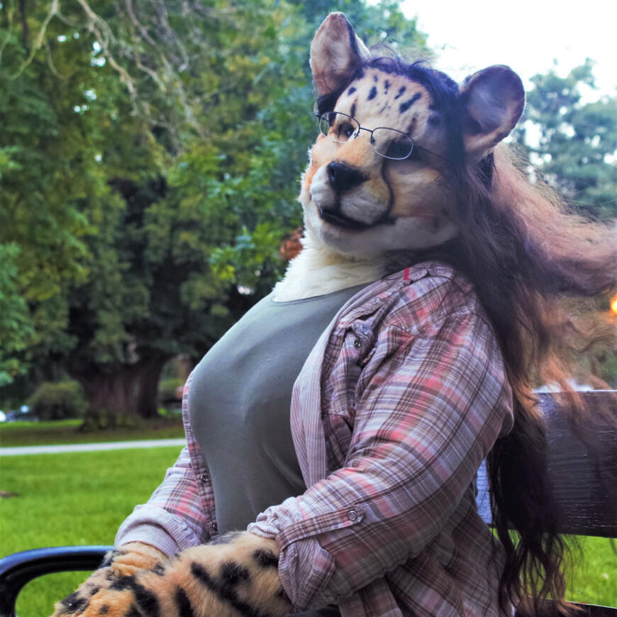 Shetani at a park, her natural wavy brown hair blowing in the wind