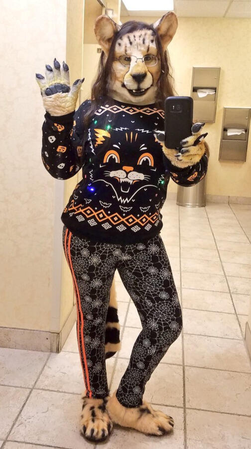 Shetani in a light-up black cat sweater and spiderweb leggings