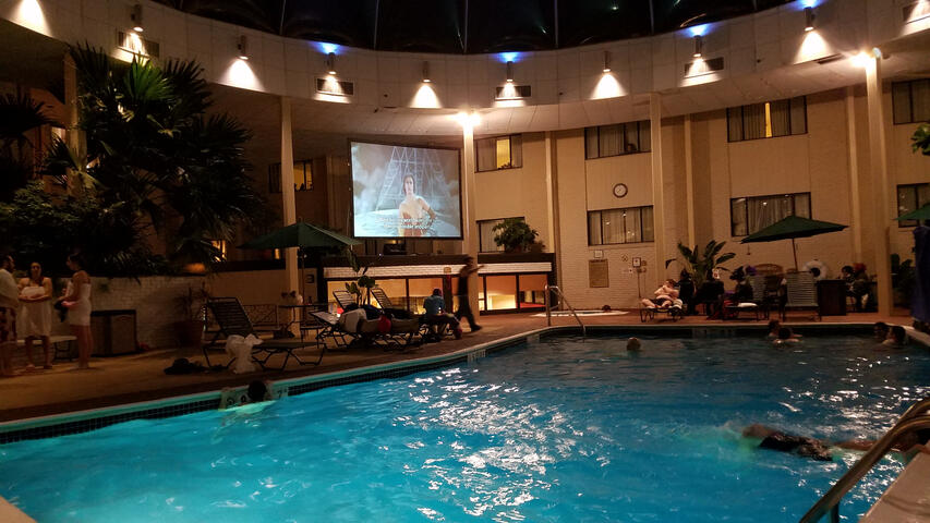 The pool at night, a projector is playing Rocky Horror over it