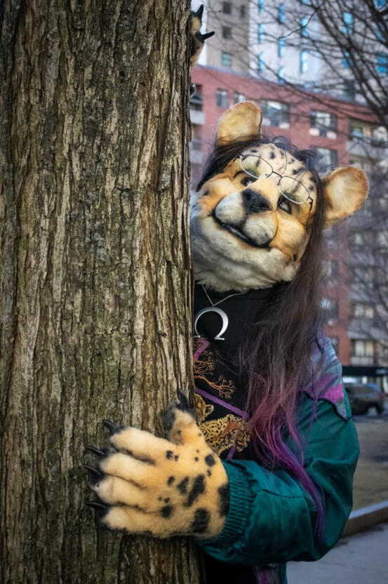 Shetani peeking out from behind a tree