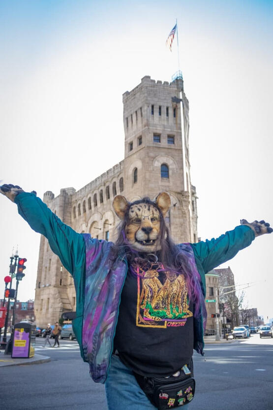Shetani gesturing with open arms to a castle Shetani gesturing with open arms to a castle