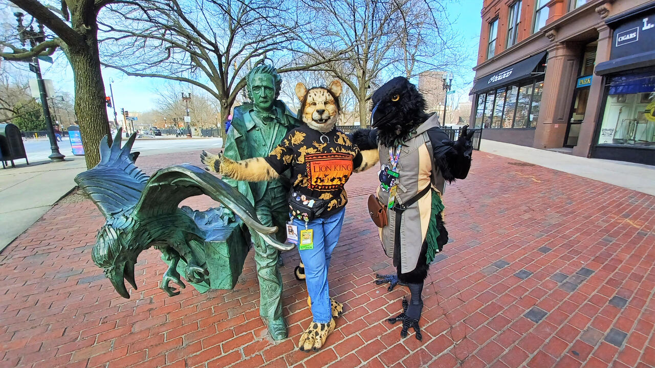 Shetani and Pine the raven next to a statue of Edgar Allan Poe with a raven