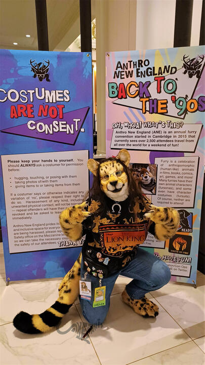 Shetani wearing a vintage 1990s allover print Lion King t-shirt, baggy jeans, and fanny pack posed in front of the Anthro New England signs