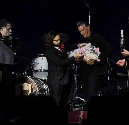 The mayor of Belleville, NJ on stage at a My Chemical Romance show being handed a sheaf of wheat and large fish by The Clerk.