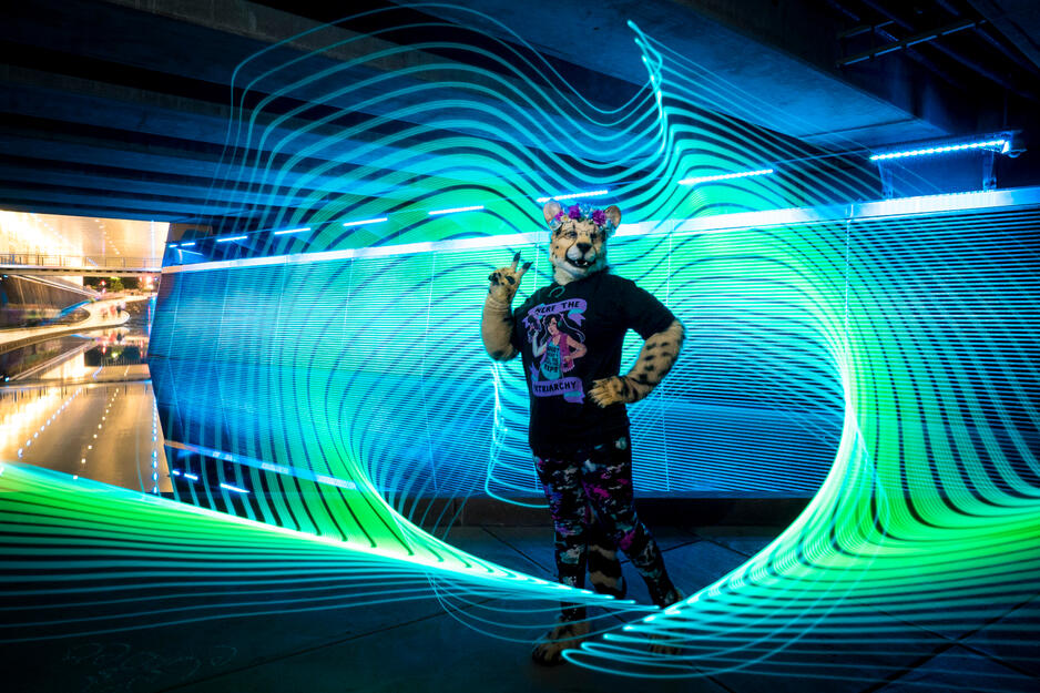 Shetani holding up the peace sign with very cool blue and green light painting around/behind her