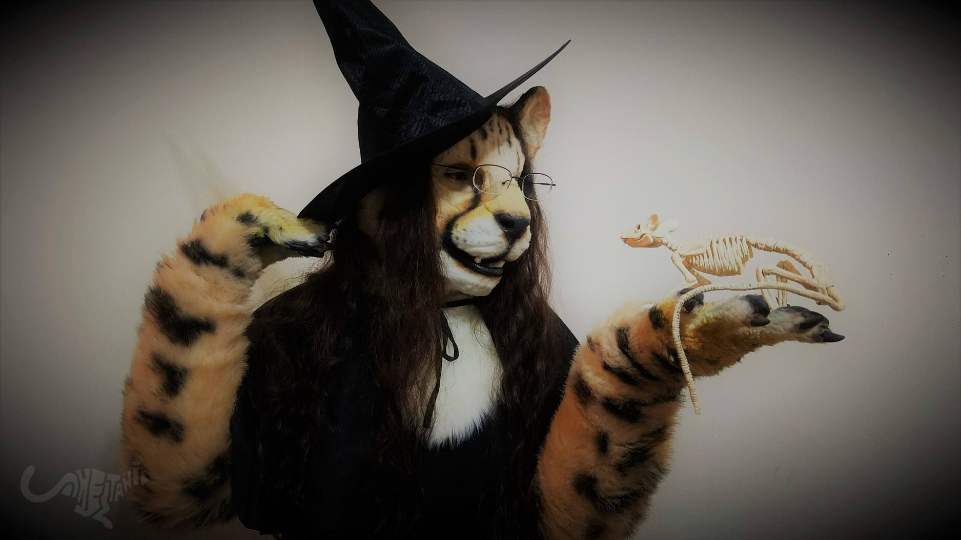 Shetani in a witch costume holding a skeleton rat. Vignette/old film editing